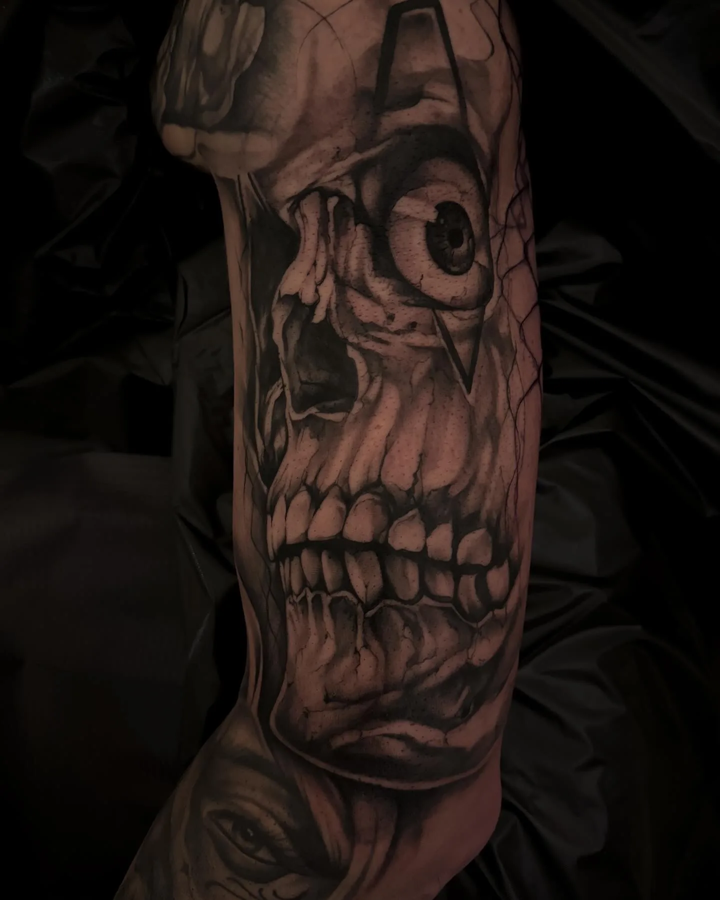 Detailreiches Black-and-Grey Tattoo von Elena mit surrealem Gesichtsmotiv